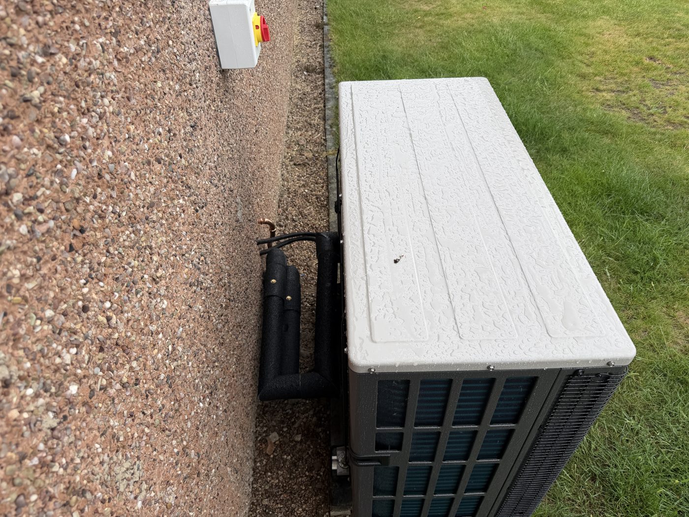 Air source heat pump outdoor unit mounted beside a property